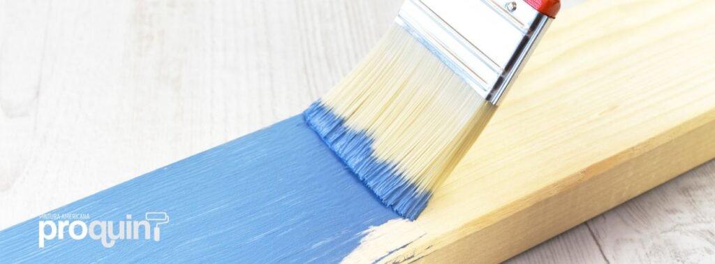 Una brocha pintando una madera en el suelo de color azul